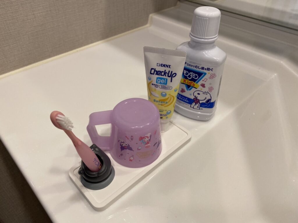 洗面台に並ぶ歯ブラシ、コップ、歯磨き粉