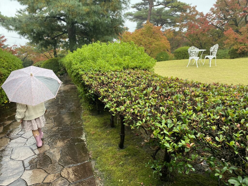 堀江オルゴール博物館の庭園とその横を歩く傘をさした女の子